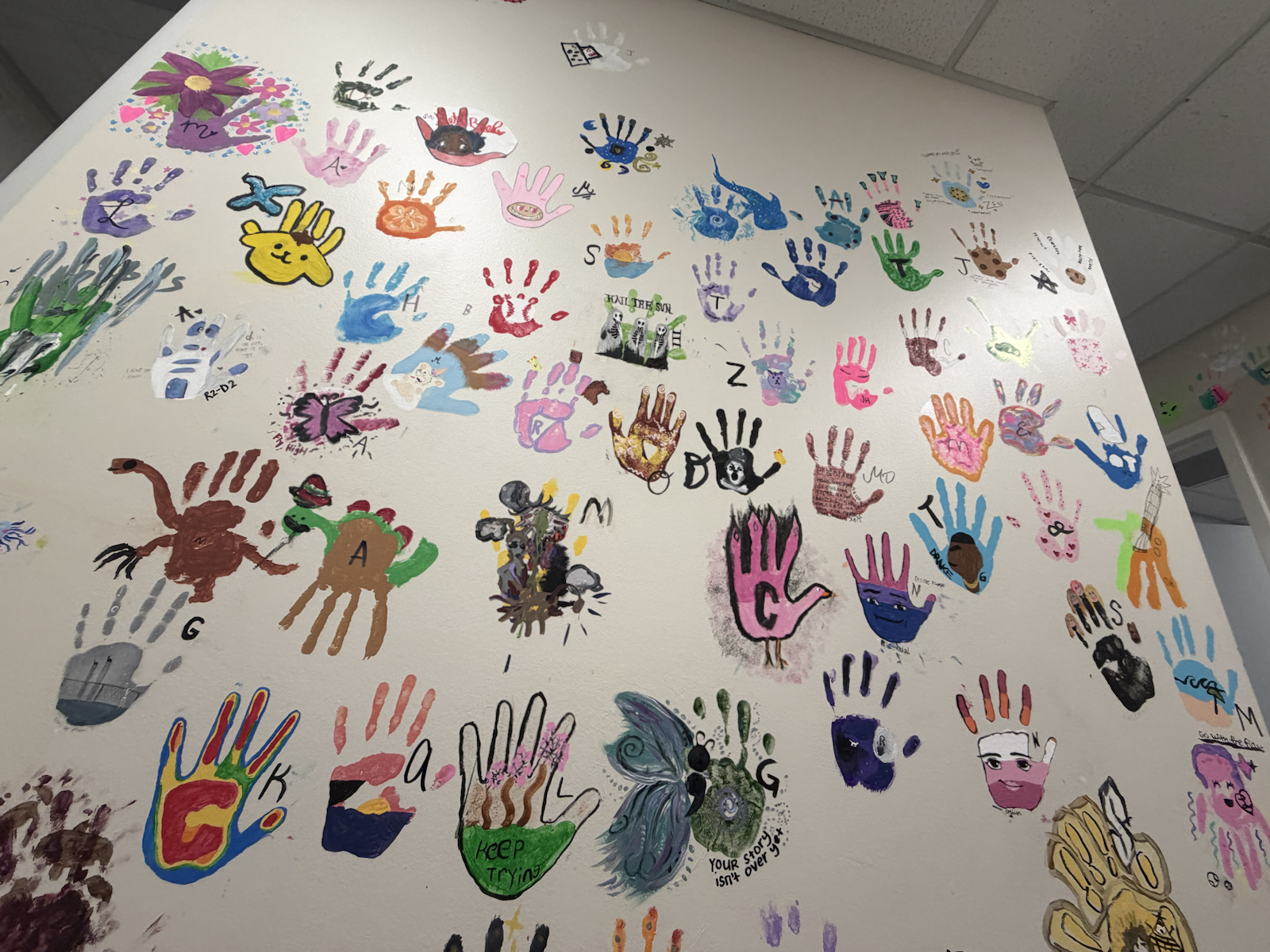 A wall covered in colorful student handprint artwork
